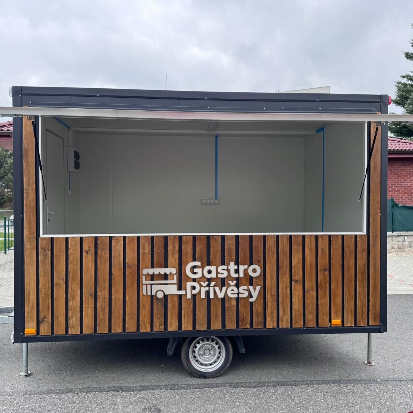 Rear view of a Gastro Přívěsy branded sales and gastro trailer with blue and wood-slat cladding