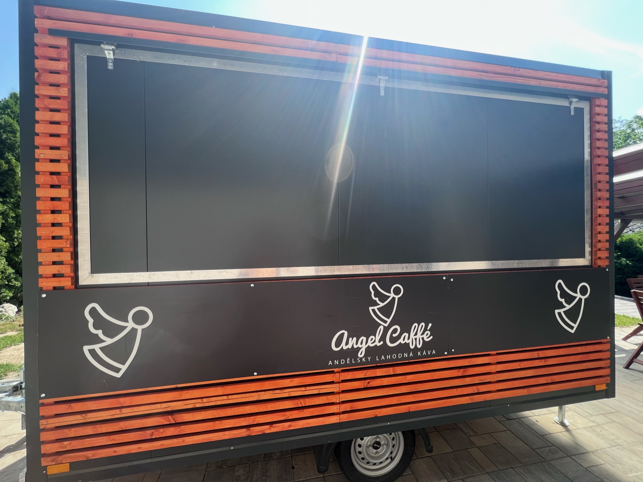 Custom-built mobile food trailer with orange wood-slat cladding and an open serving window